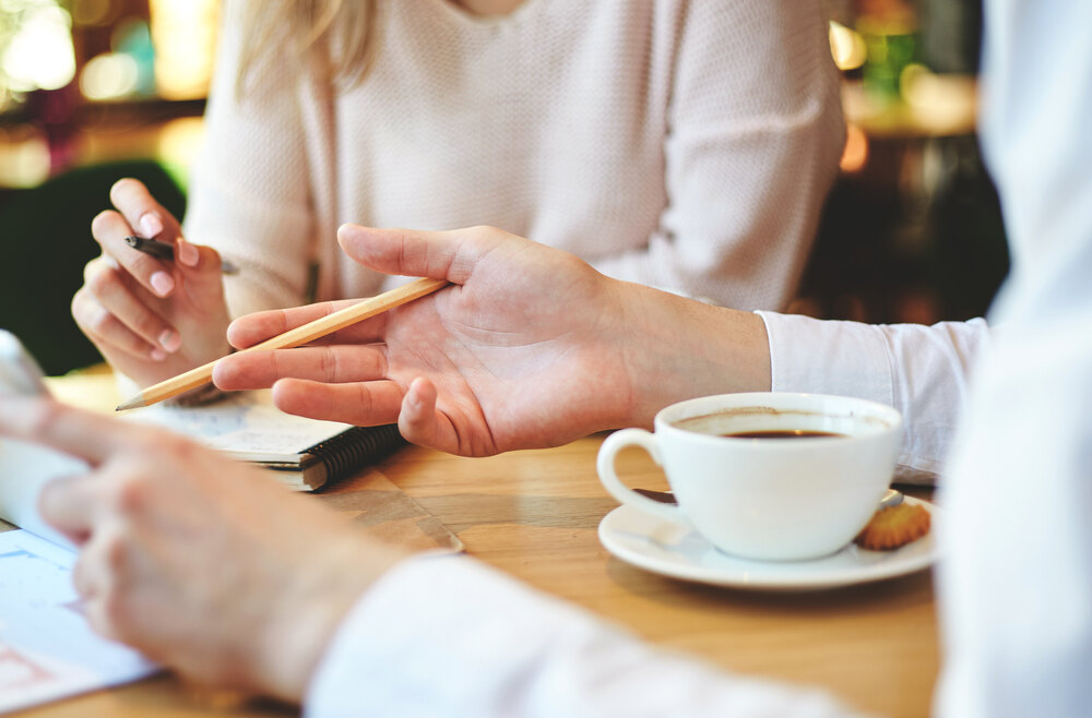 Two people discussing documents over coffee