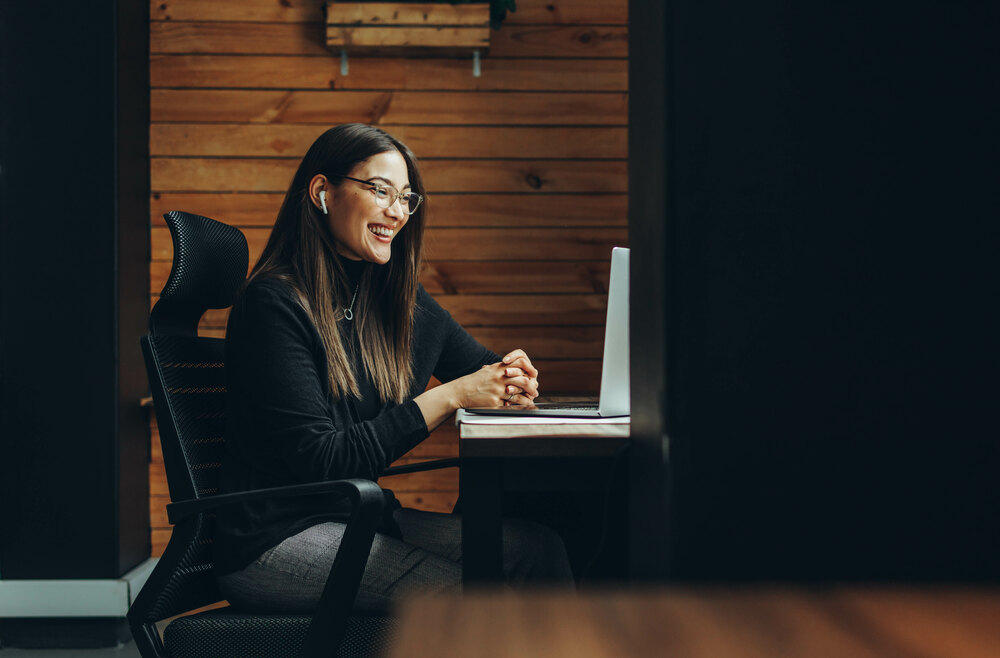A woman smiling while working at a laptop